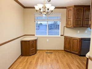 Kitchen with light hardwood / wood-style floors, an inviting chandelier, hanging light fixtures, and ornamental molding