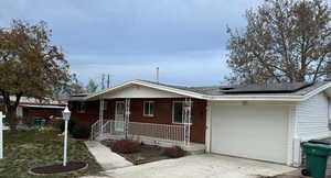 Single story home featuring solar panels and a garage