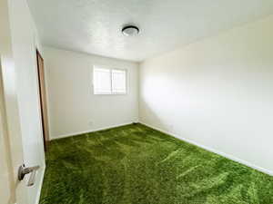 Unfurnished room with dark carpet and a textured ceiling