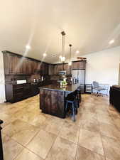 Kitchen featuring decorative backsplash, appliances with stainless steel finishes, dark stone counters, decorative light fixtures, and a kitchen island