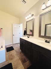 Bathroom with vanity, lofted ceiling, and a tub