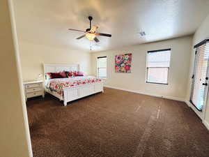 Carpeted bedroom featuring a textured ceiling, multiple windows, and ceiling fan