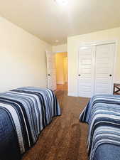 Carpeted bedroom featuring a textured ceiling and a closet