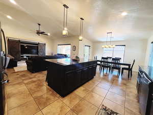 Kitchen with pendant lighting, a center island, lofted ceiling, ceiling fan with notable chandelier, and a textured ceiling