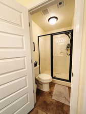 Bathroom featuring a textured ceiling, an enclosed shower, and toilet