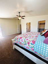 Carpeted bedroom with a textured ceiling, a walk in closet, a closet, and ceiling fan