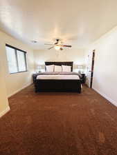 Carpeted bedroom featuring ceiling fan and a textured ceiling