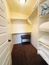 Walk in closet with vaulted ceiling and dark carpet