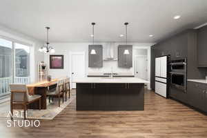 Kitchen with wall chimney exhaust hood, white refrigerator, decorative light fixtures, a notable chandelier, and light hardwood / wood-style floors