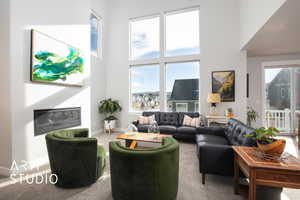 Carpeted living room with a healthy amount of sunlight and a high ceiling