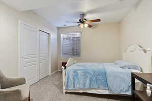 Carpeted bedroom featuring ceiling fan and a closet