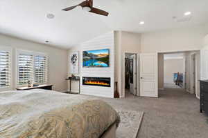 Bedroom featuring vaulted ceiling, ceiling fan, a spacious closet, a fireplace, and a closet