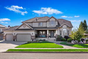 View of front of property featuring covered porch, a garage, and a front lawn