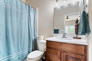 Bathroom featuring ceiling fan, toilet, walk in shower, and vanity