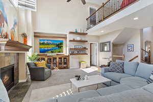 Living room featuring a tile fireplace, a towering ceiling, and ceiling fan