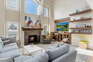 Living room featuring a tile fireplace, light carpet, and a high ceiling