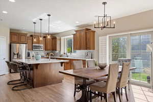 Kitchen featuring plenty of natural light, an island with sink, hanging light fixtures, and appliances with stainless steel finishes