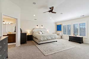 Bedroom featuring ceiling fan, sink, light carpet, and ensuite bath