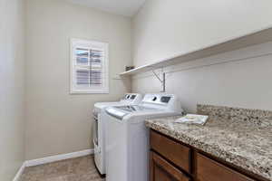 Clothes washing area featuring washer and clothes dryer and light tile patterned floors