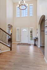 Foyer featuring light wood-type flooring, a towering ceiling, and a chandelier