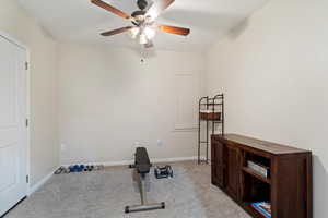 Exercise area featuring light colored carpet and ceiling fan