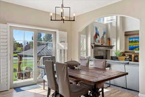 Dining area featuring a tile fireplace, light hardwood / wood-style floors, and an inviting chandelier