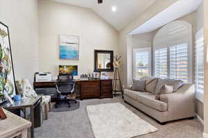 Carpeted home office with high vaulted ceiling