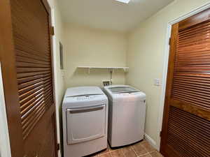 Laundry room with light tile patterned floors and washing machine and clothes dryer