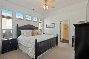 Carpeted bedroom featuring ensuite bathroom and ceiling fan