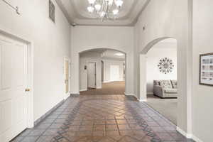 Hallway with carpet, a towering ceiling, and a chandelier