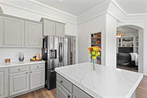 Kitchen with gray cabinets, dark hardwood / wood-style flooring, a kitchen island, and stainless steel refrigerator with ice dispenser