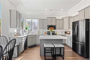 Kitchen featuring a center island, light hardwood / wood-style floors, gray cabinets, and black appliances