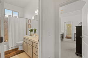 Full bathroom with toilet, vanity, shower / bath combination with curtain, and wood-type flooring