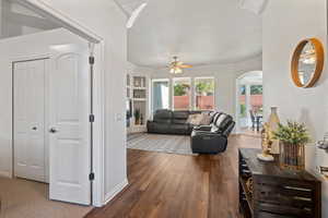 Living room with ceiling fan, dark hardwood / wood-style flooring, and built in shelves