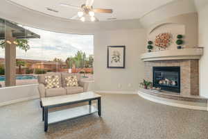 Living room with carpet flooring, a tile fireplace, and ceiling fan