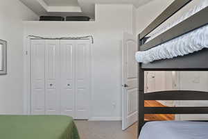 Bedroom with light colored carpet and a closet