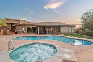 Pool at dusk with a patio area and an in ground hot tub