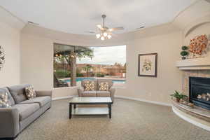 Carpeted living room with a tile fireplace and ceiling fan