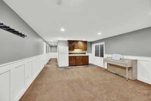 Kitchen with white fridge, light colored carpet, and sink