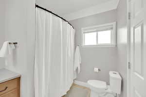 Bathroom featuring tile patterned floors, a shower with curtain, toilet, and ornamental molding