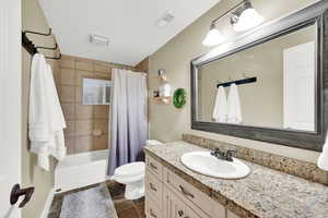 Bathroom featuring vanity, tile patterned floors, toilet, a textured ceiling, and curtained shower