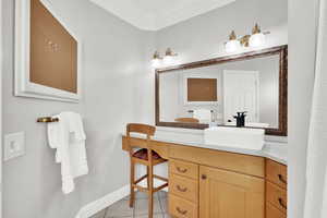 Bathroom with crown molding, tile patterned flooring, and vanity