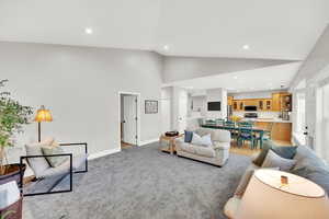 Carpeted living room featuring high vaulted ceiling