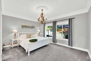 Bedroom featuring dark colored carpet, crown molding, and a notable chandelier