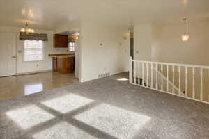 Unfurnished living room featuring a chandelier