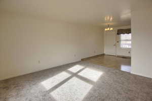 Unfurnished room with a chandelier and carpet flooring