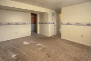 Empty room with carpet flooring and a textured ceiling