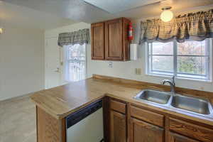 Kitchen featuring kitchen peninsula, a textured ceiling, white dishwasher, and sink