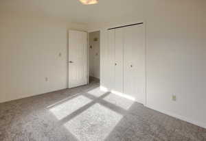 Unfurnished bedroom featuring a closet and light colored carpet