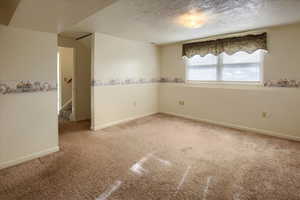 Empty room with a textured ceiling and light carpet